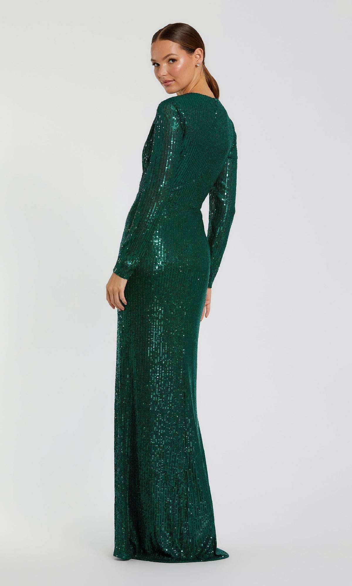 A woman faces backward against a plain white background, wearing the Mac Duggal 11659 Long Sleeve Sequin Formal Dress, a fitted green evening gown with long sleeves and sparkling sequins.